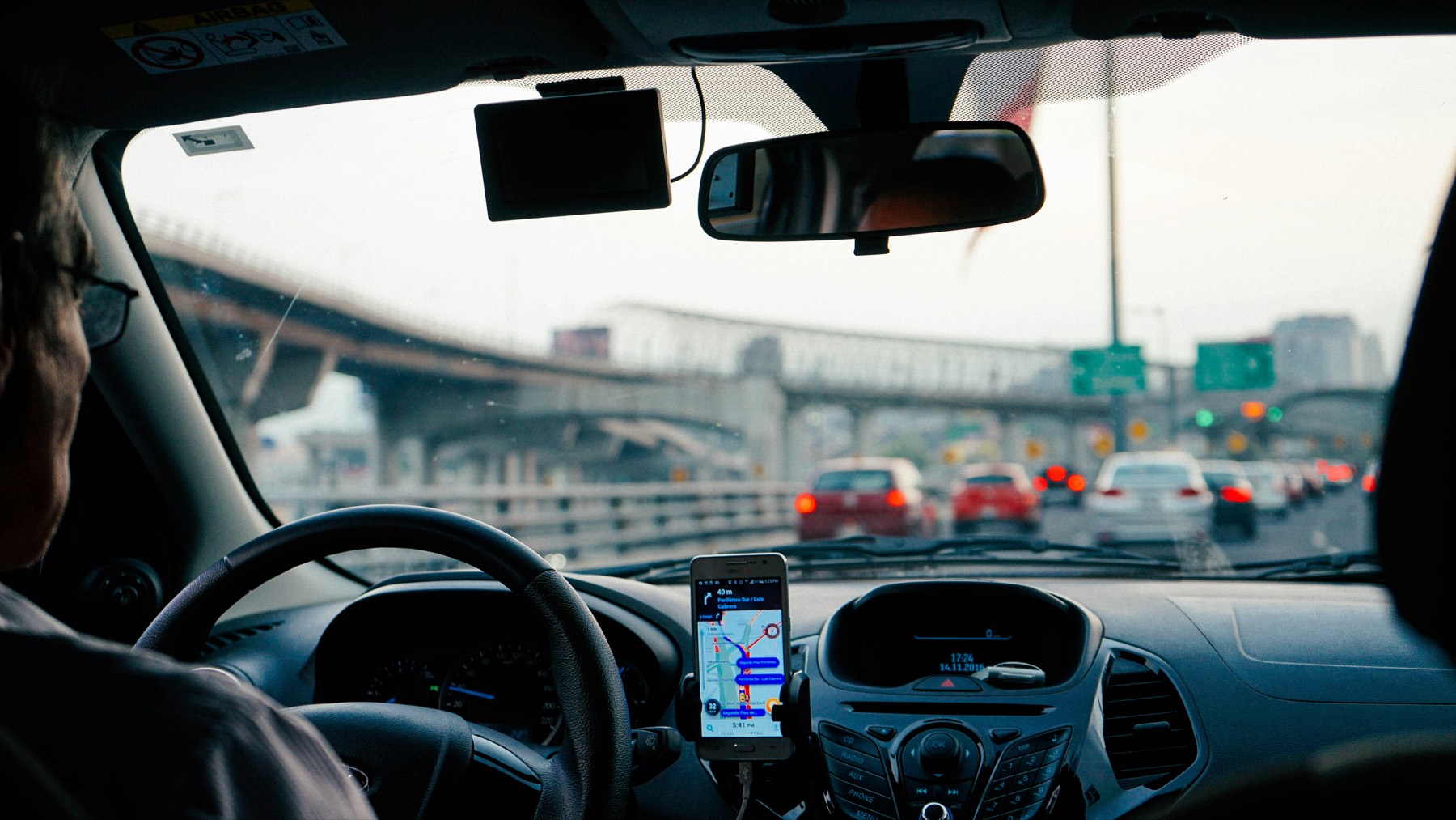 A learner driving through busy city traffic with sat-nav guidance